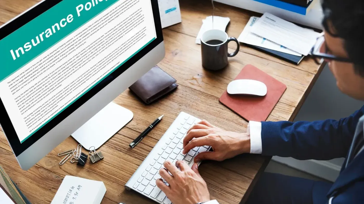 Man working at a computer looking at an Insurance Policy