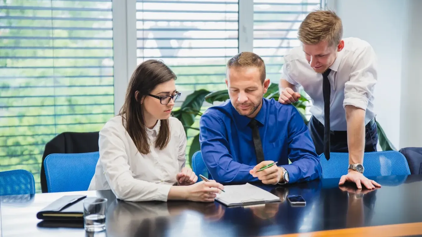 A woman and two men working in an office going over paperwork