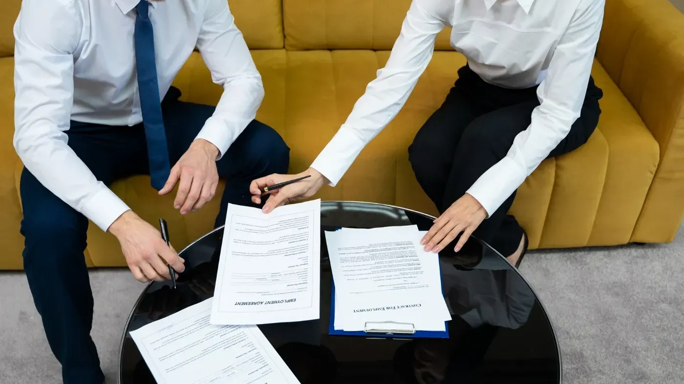 Two people talking with sheets of paper in front of them on a table