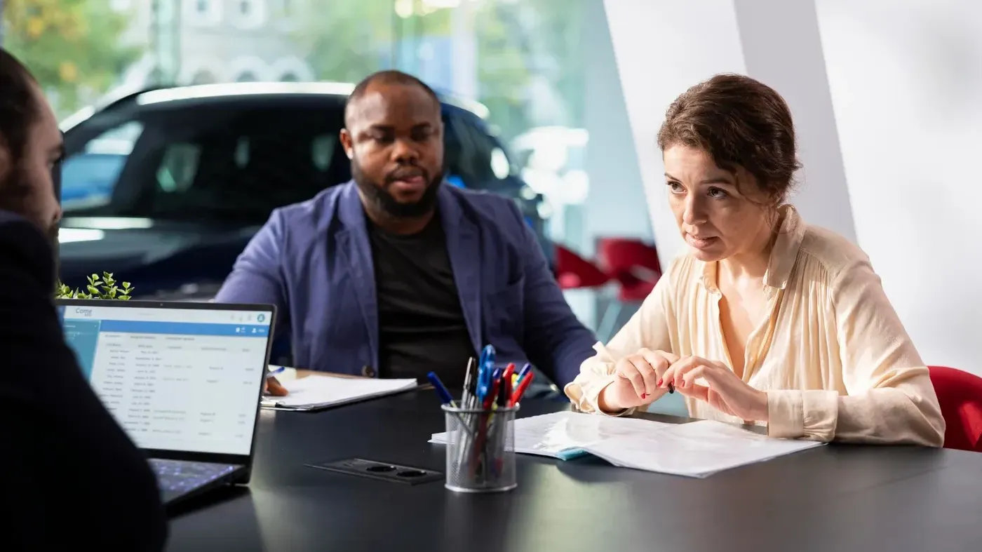 A man and a woman at a car dealership filling out paperwork